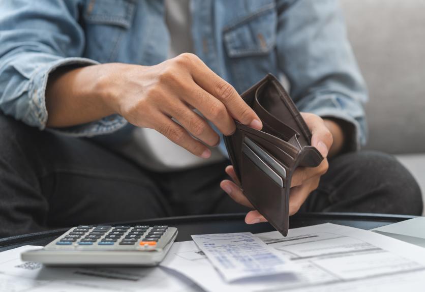 Person checking empty wallet while managing bills — visualizing the need for digital wallets in Lebanon due to cash limitations and financial pressure.
